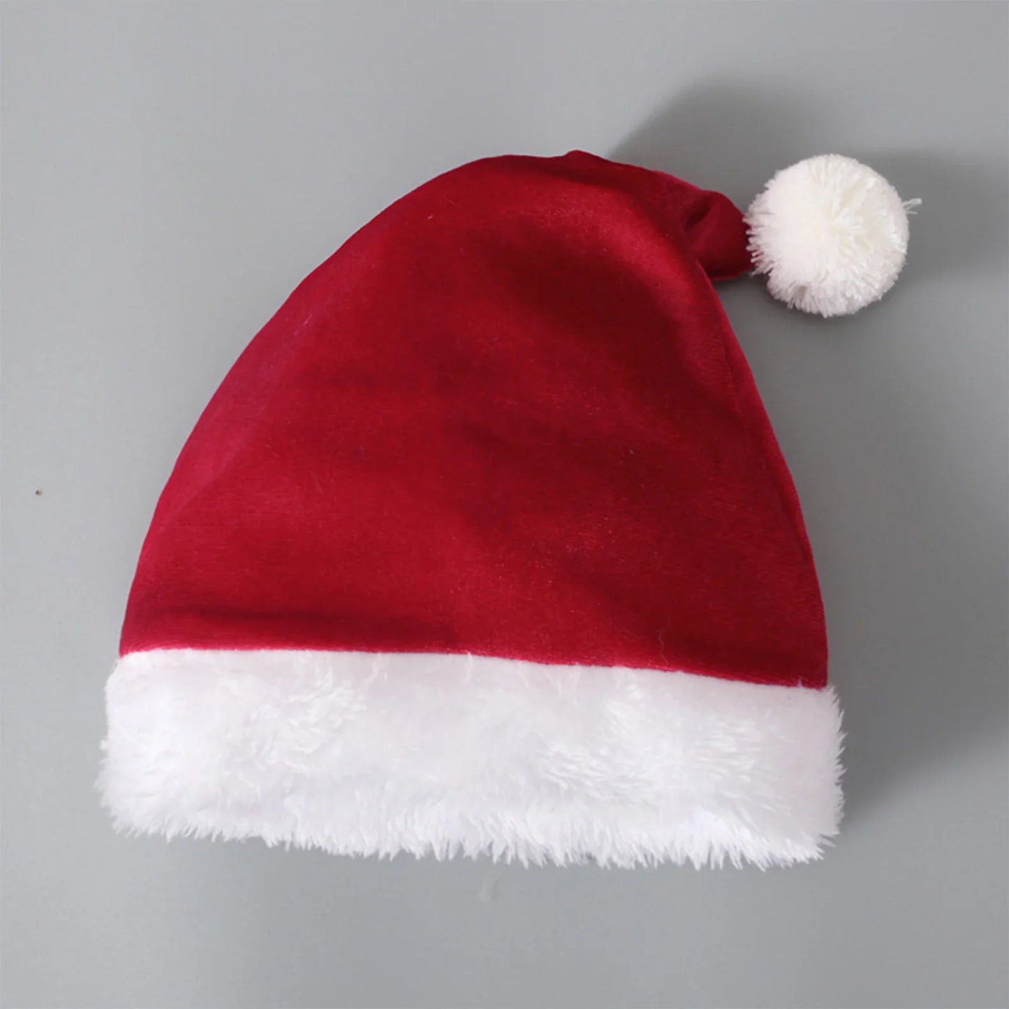Classic red Santa hat with white faux fur trim and pom-pom on a plain gray background