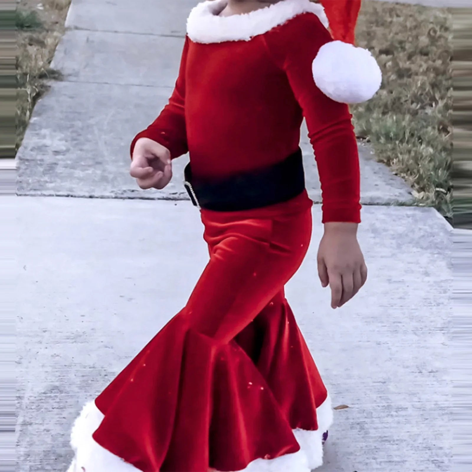Child in red Santa-inspired costume with flared pants and faux fur trim outdoors