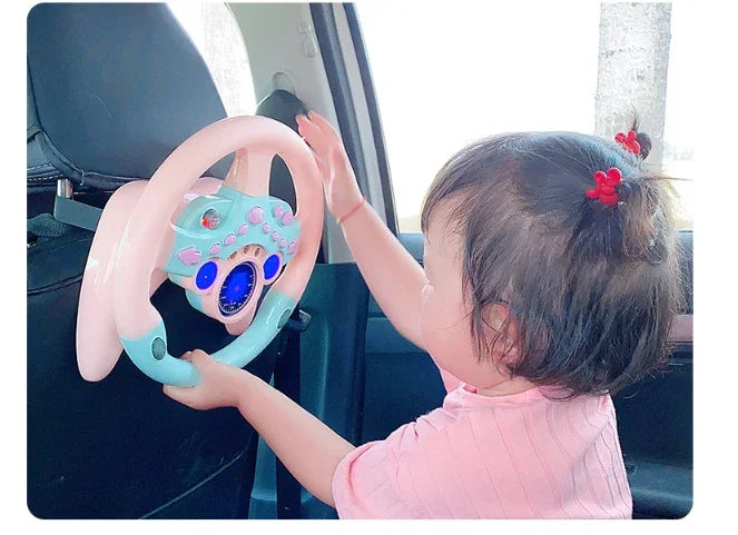 Toddler playing with pink toy steering wheel in car, kids driving toy accessory