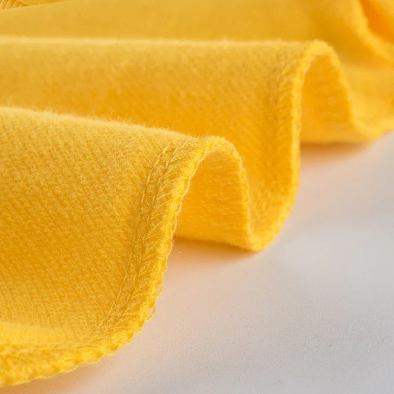 Close-up of soft yellow microfiber towel fabric on white surface