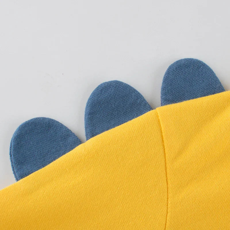 Close-up of yellow fabric with blue dinosaur spikes detail, kids clothing accessory