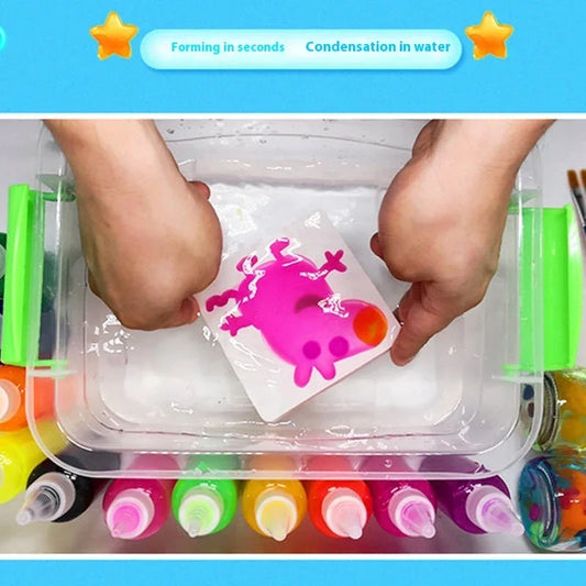 Hands creating a pink animal shape in water with colorful liquid art supplies below.
