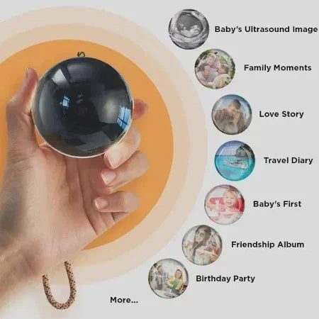 Hand holding a black photo locket sphere with icons for ultrasound, family, love, travel, baby, friends, and birthday memories.