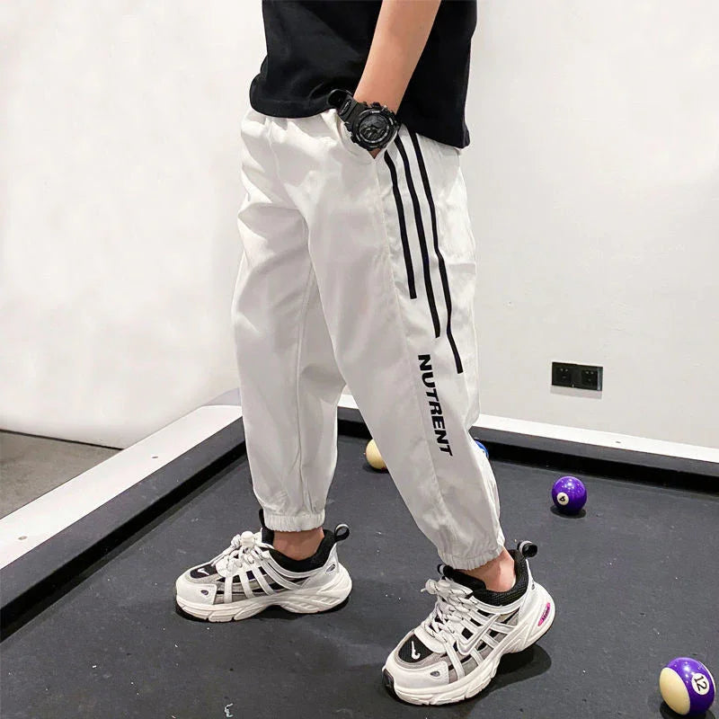Person in white jogger pants with black stripes and 'NUTRENT' text, standing by a pool table